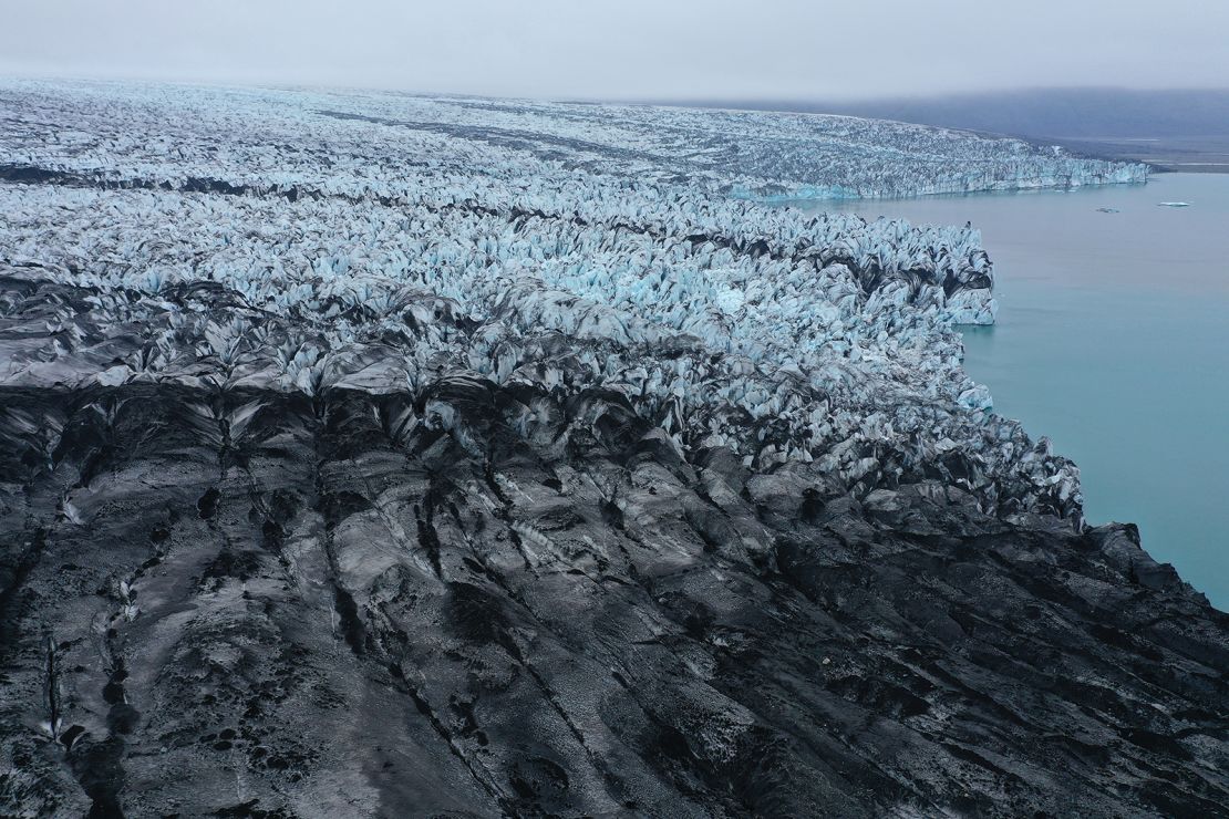 Cofający się lodowiec Breidamerkurjokull, którego część jest czarna od pyłu wulkanicznego i kamieni, kończy się przy jeziorze Jokulsarlon 15 sierpnia 2021 r. w pobliżu Hof na Islandii.