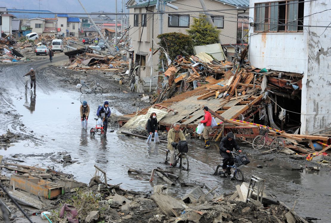 Mieszkańcy przechodzą przez zdewastowaną ulicę w Ishinomaki, w prefekturze Miyagi, po tym, jak Japonię nawiedziło niszczycielskie trzęsienie ziemi i tsunami, 15 marca 2011 r.