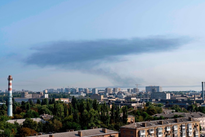 Gęsty dym unoszący się nad panoramą Kijowa na Ukrainie po poważnym ataku rakietowym Rosji. Krajobraz miejski obejmuje budynki mieszkalne i przemysłowe, z widocznym kominem na pierwszym planie.